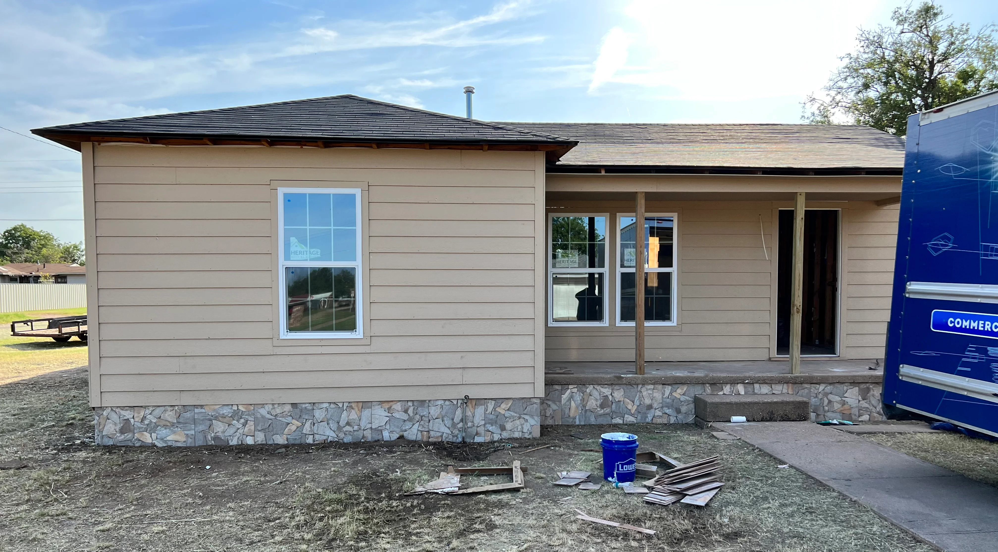 Modern home remodel with tan siding, stone foundation, new windows, and metal roof in Spring, TX
