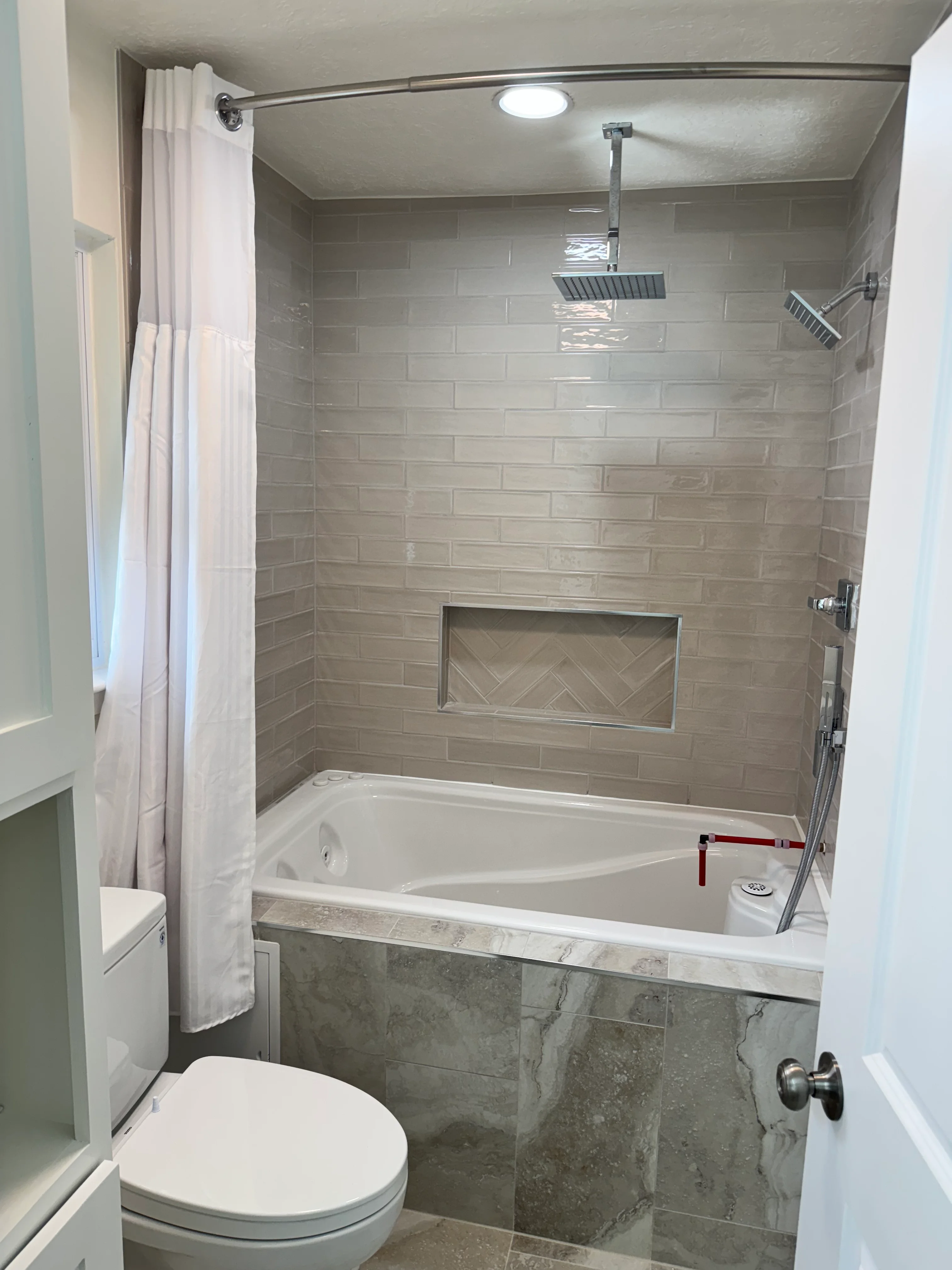 Modern bathroom with gray subway tile shower, soaking tub, and marble accents