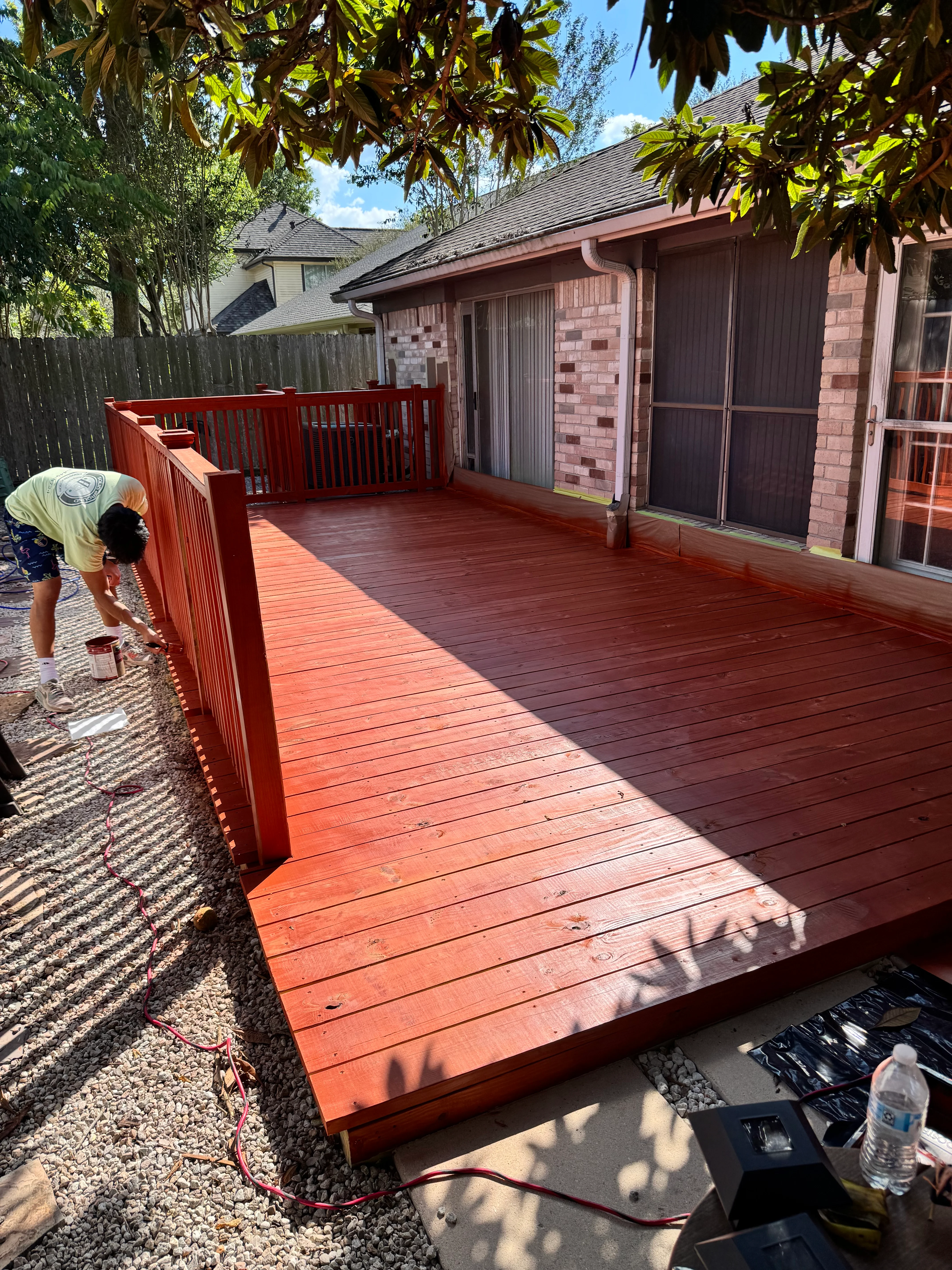 Red composite deck with railings under construction at residential home in Spring, TX