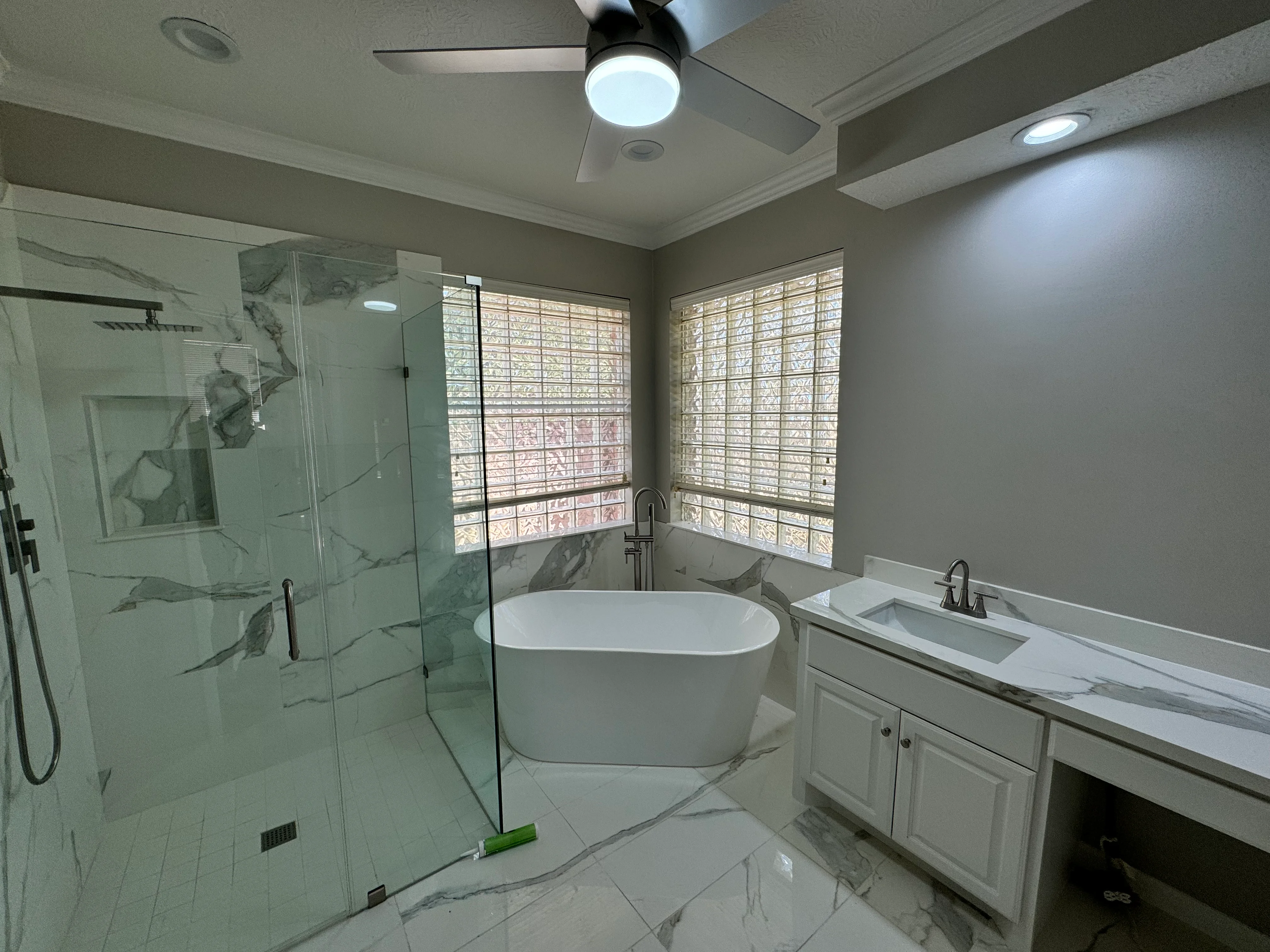 Modern master bathroom with white freestanding tub, glass shower, and marble finishes