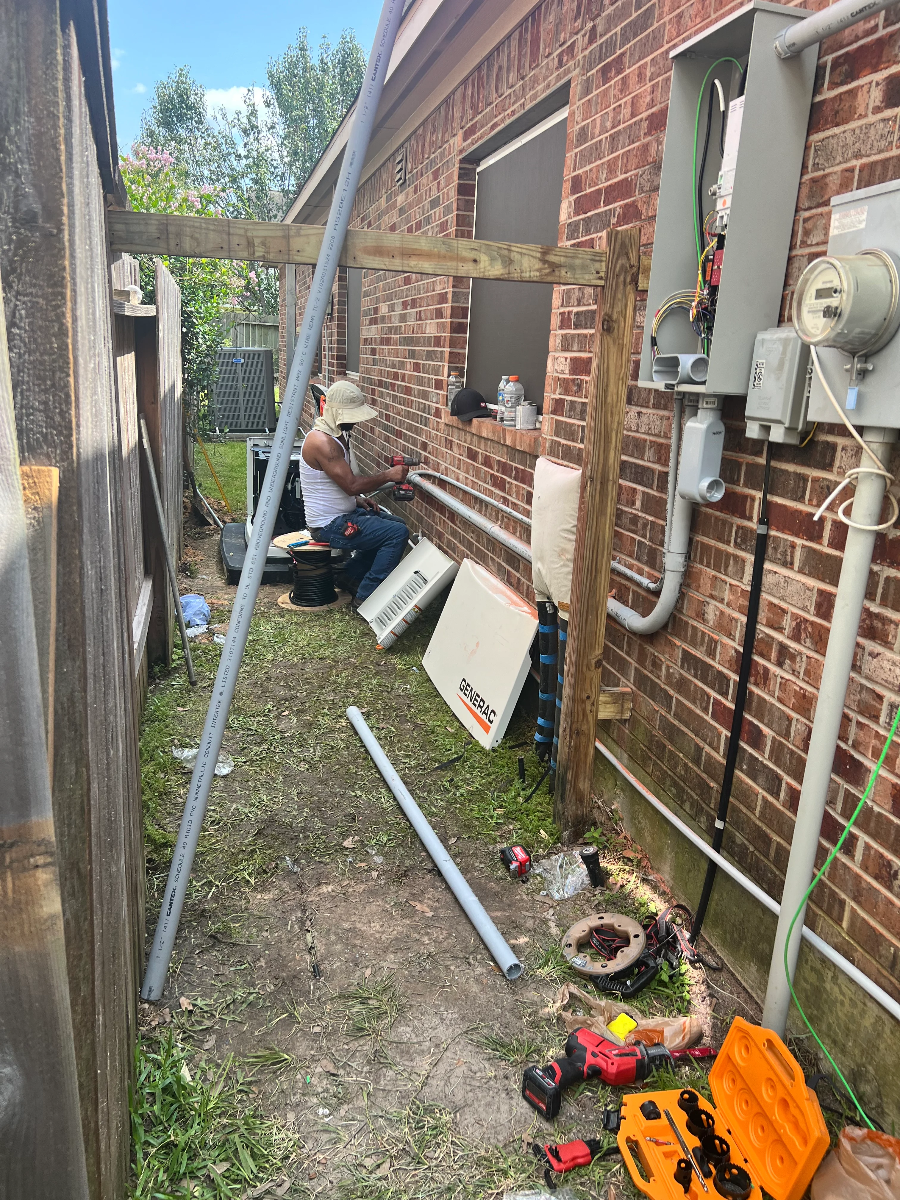 Electrician installing new service panel and conduit on brick home exterior