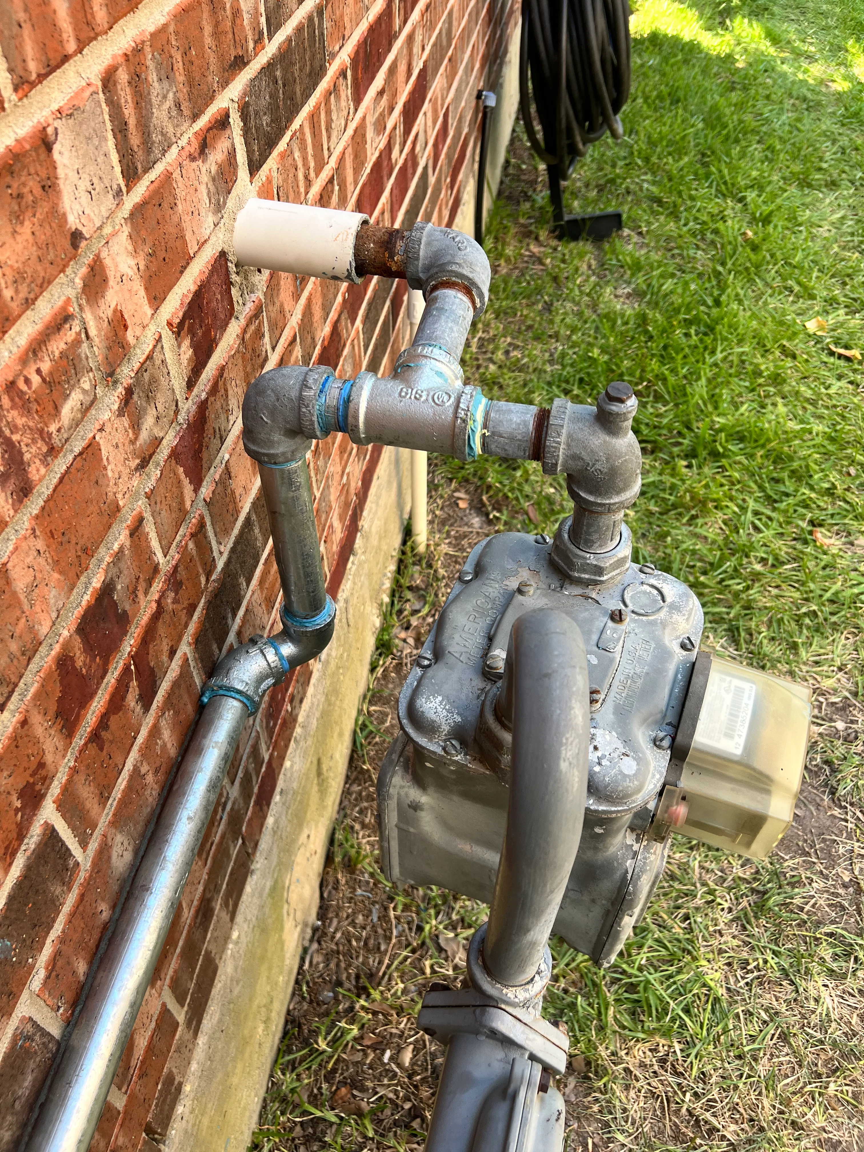 Cast iron plumbing pipes with blue couplings mounted on red brick exterior wall