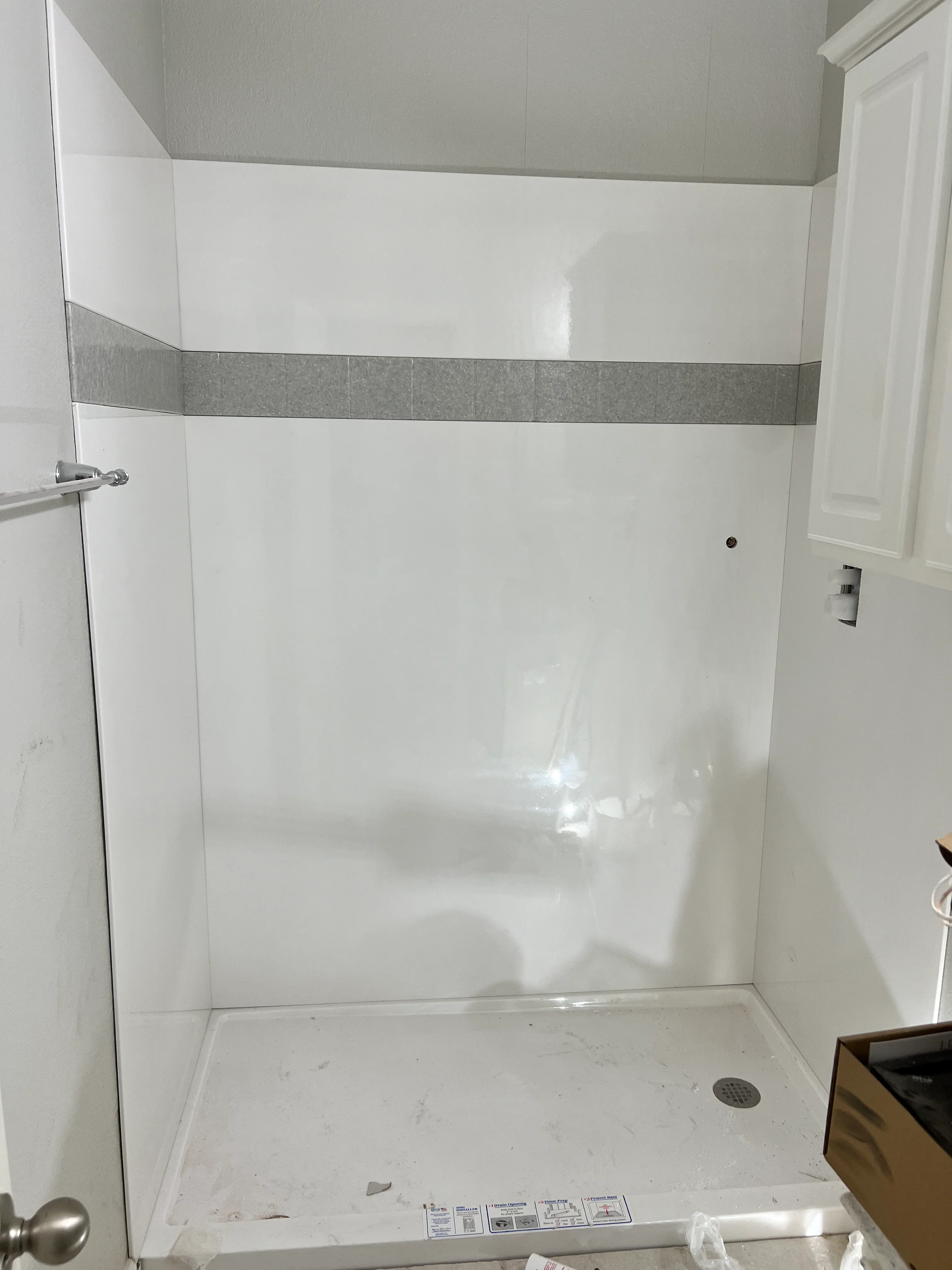 White subway tile shower enclosure with gray accent stripe and frameless glass door