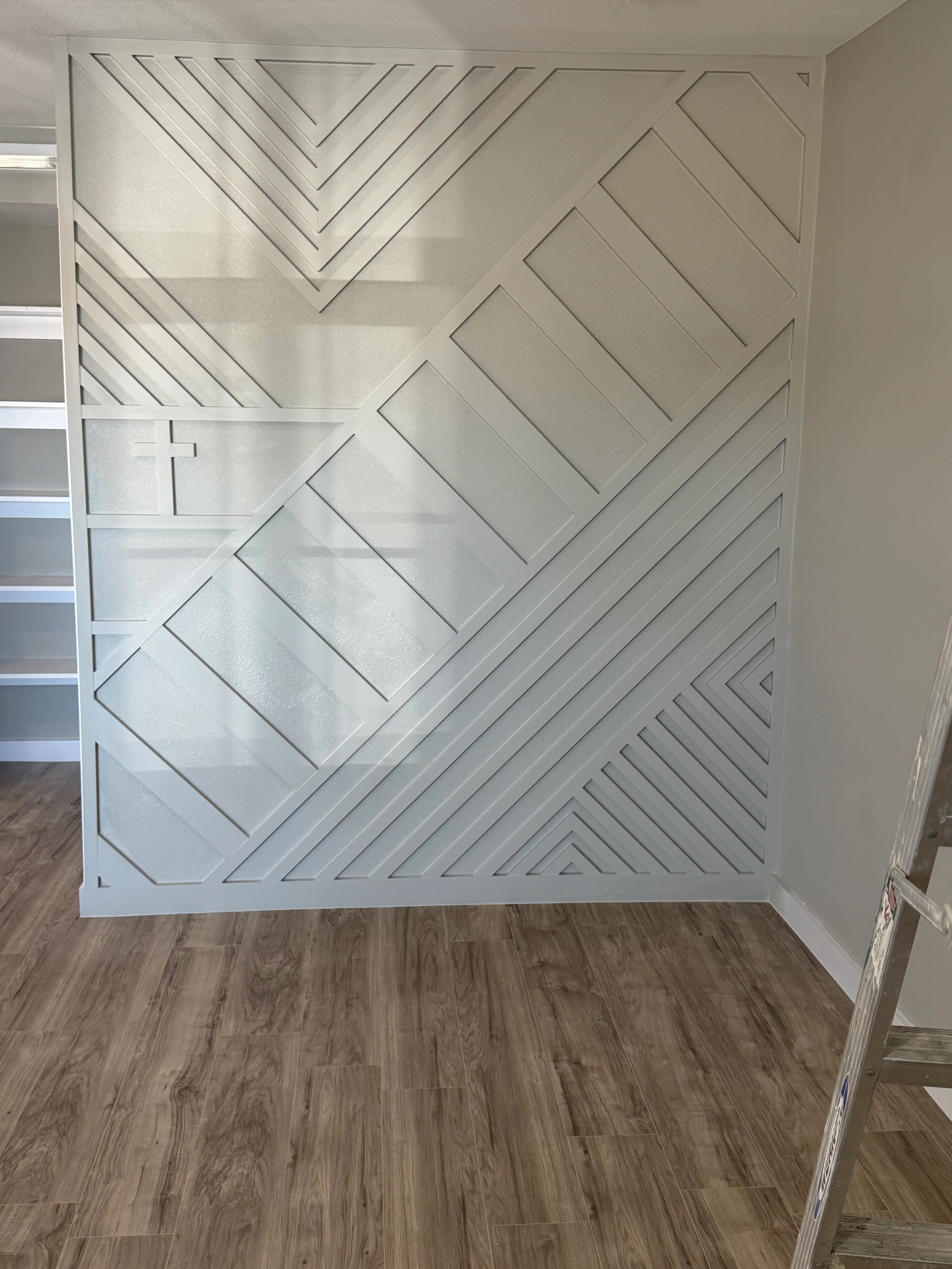 Geometric drywall accent wall with herringbone and chevron patterns in white finish