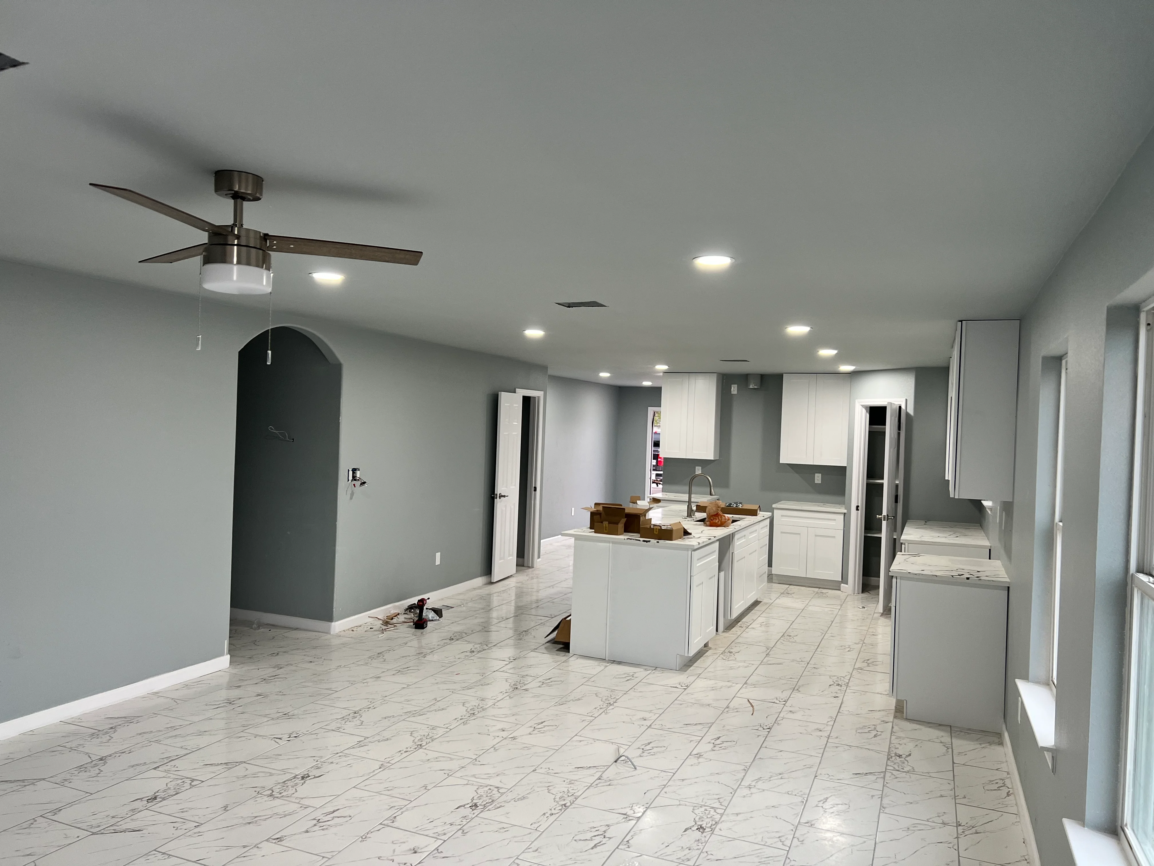 Modern kitchen remodel with white cabinets, marble tile flooring, and island in Spring home