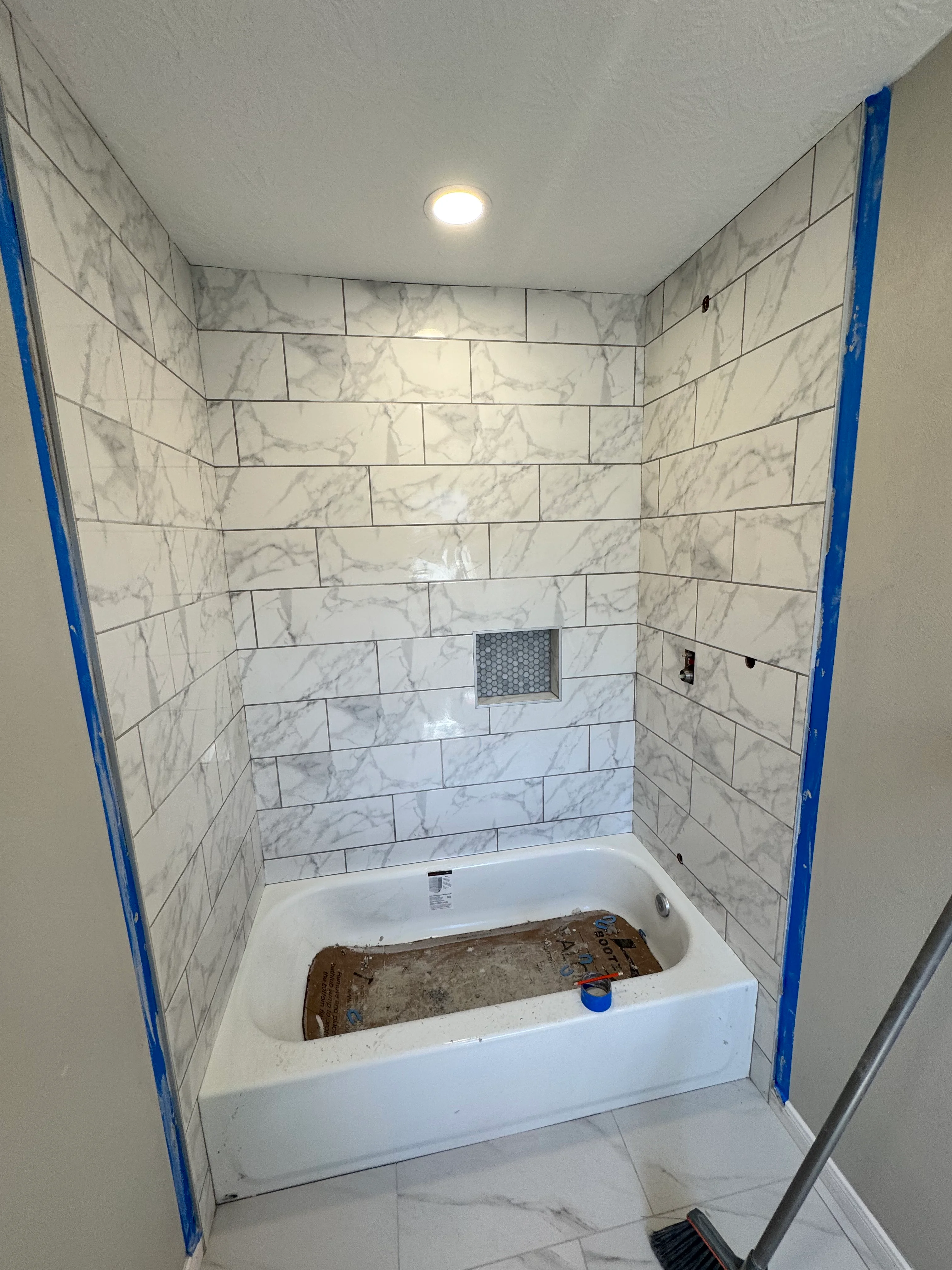 Marble subway tile bathroom surround with white soaking tub and recessed niche detail