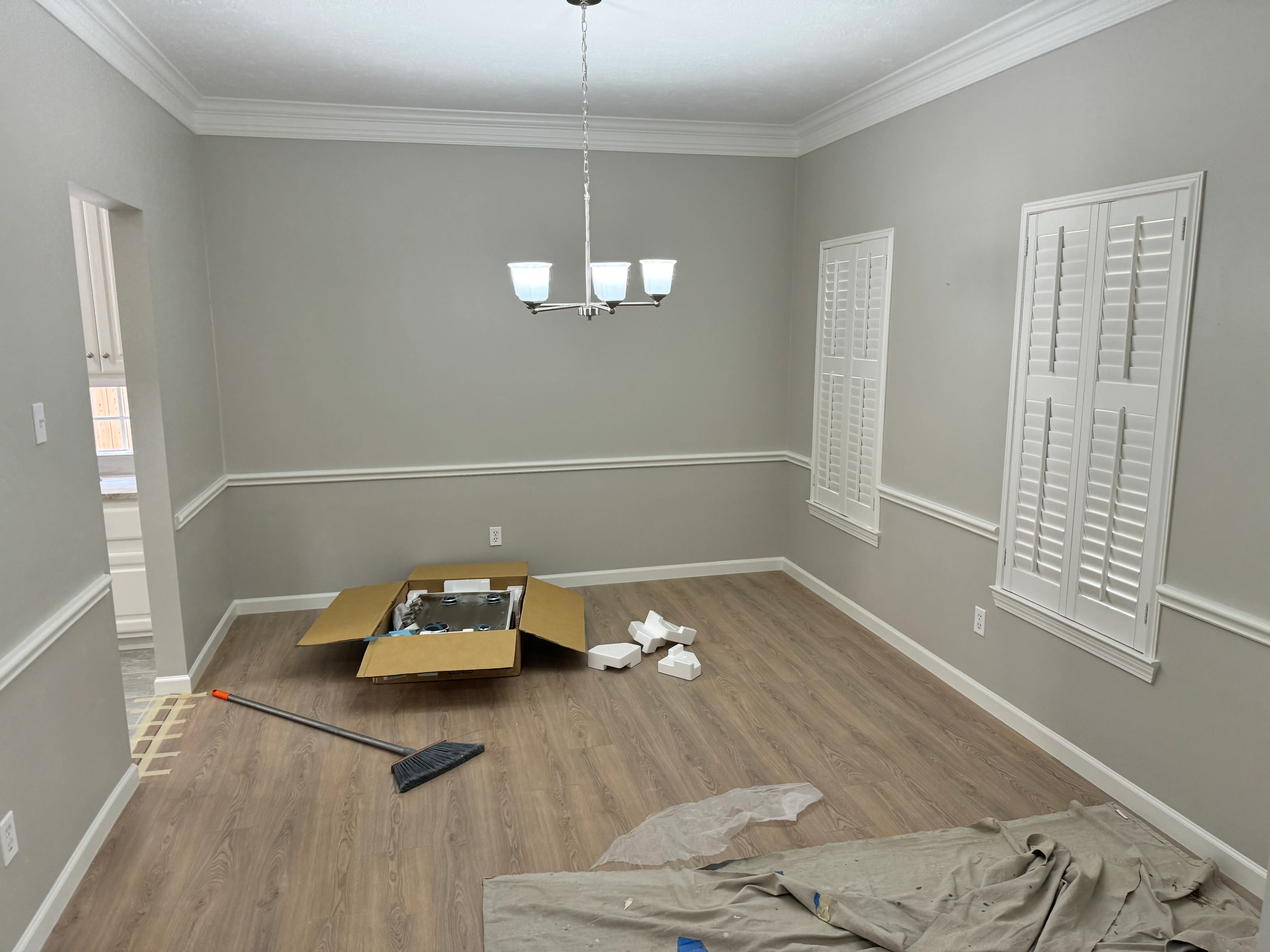 Newly remodeled dining room with gray walls, white trim, vinyl plank flooring, and pendant light