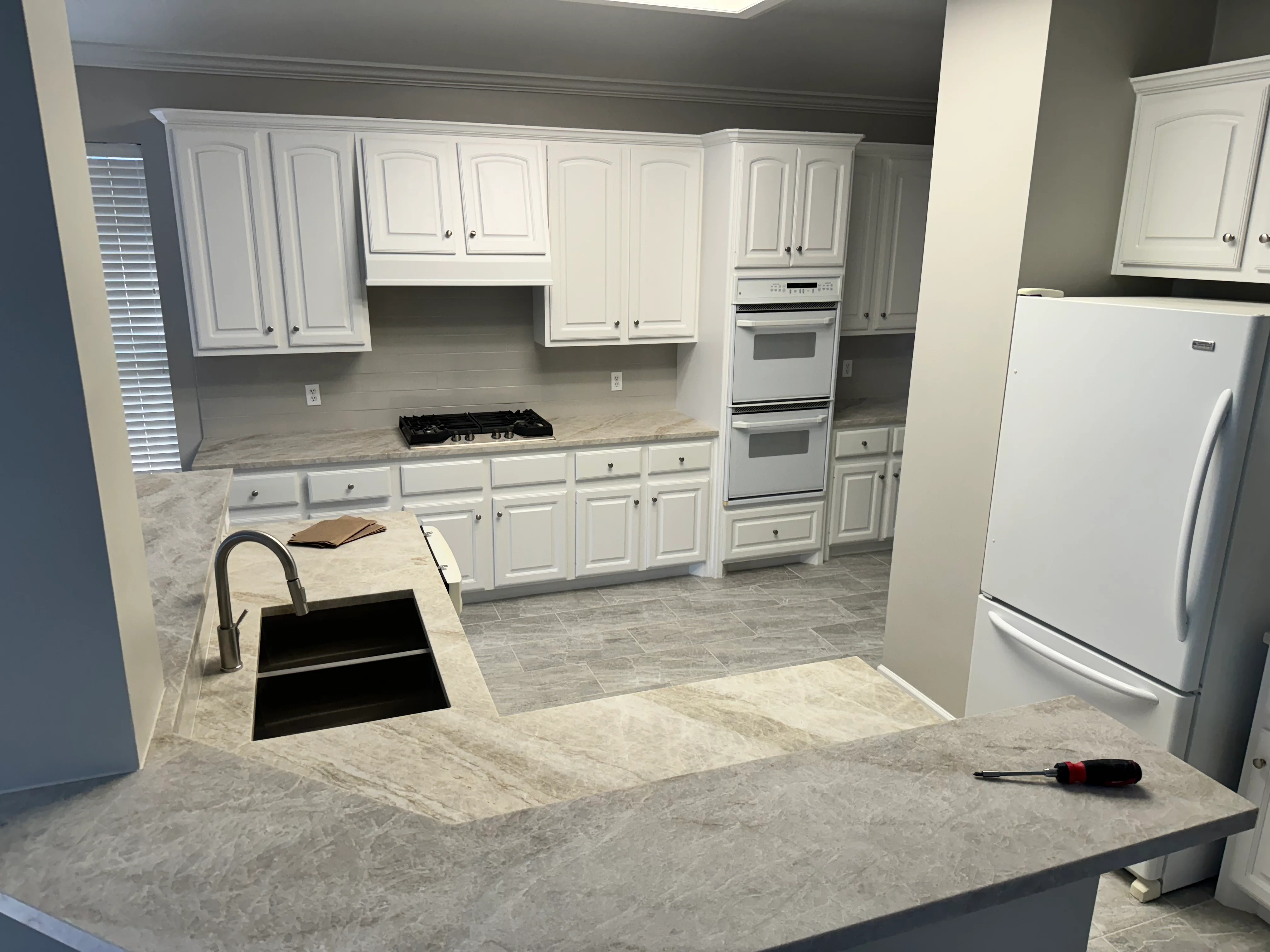 Modern kitchen with white cabinets, quartz countertops, and stainless steel appliances