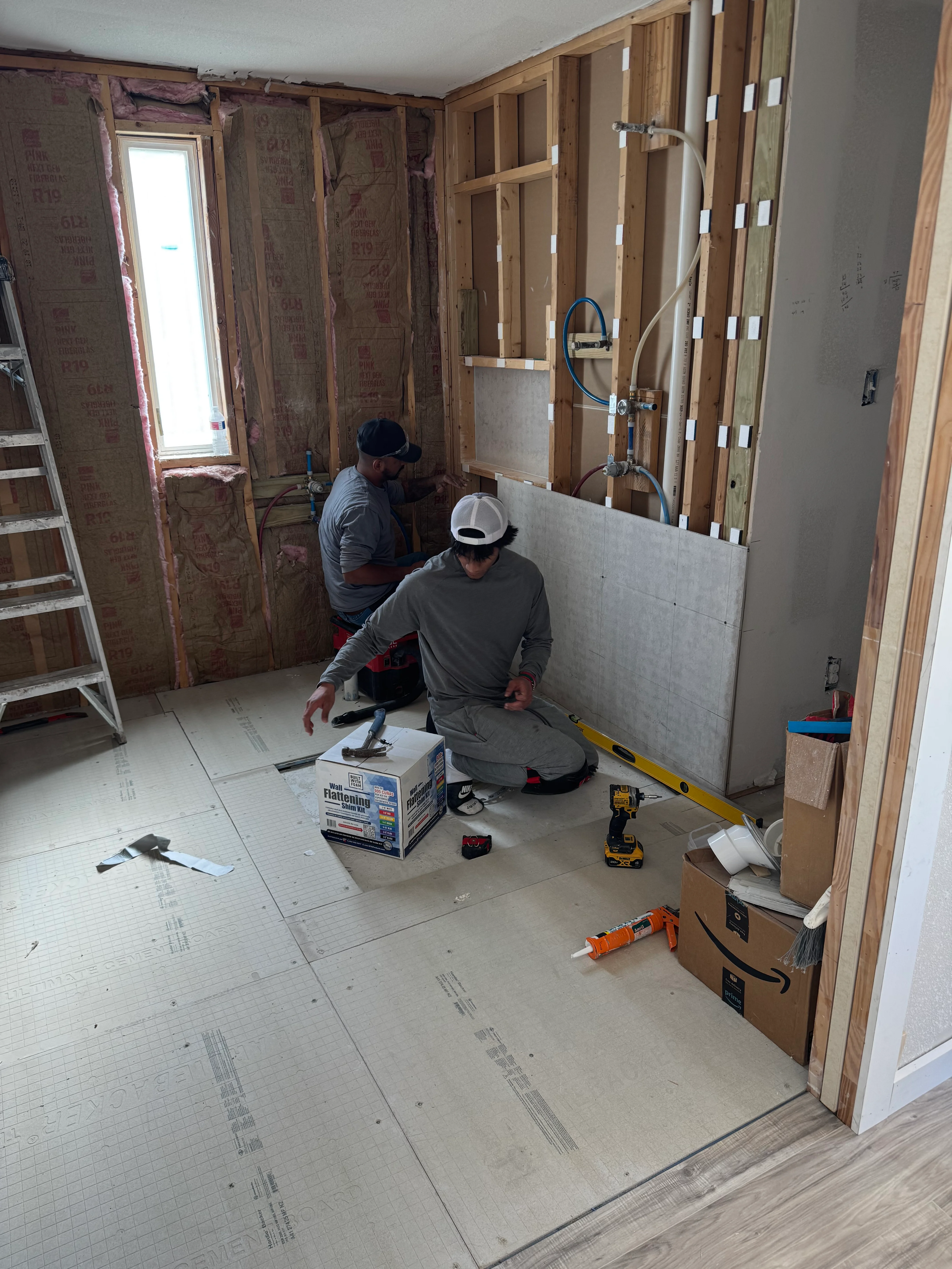 Bathroom remodel in progress with framing, drywall, and plumbing rough-in visible